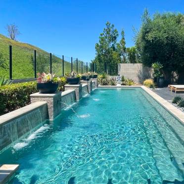 Rectangle Swimming Pool with Neutral Colors and  Water Feature Wall Along the Back